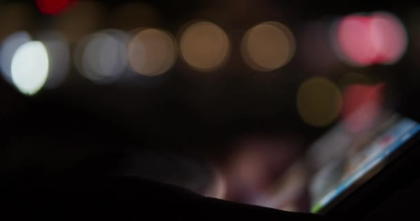 Persona que usa un dispositivo de tableta digital por la noche con luces de la ciudad en el fondo: imágenes borrosas del concepto fuera de foco
 - Imágenes, Vídeo