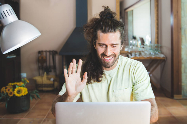 νεαρός άνδρας με φορητό υπολογιστή εργασίας και βίντεο καλώντας από το σπίτι - Φωτογραφία, εικόνα