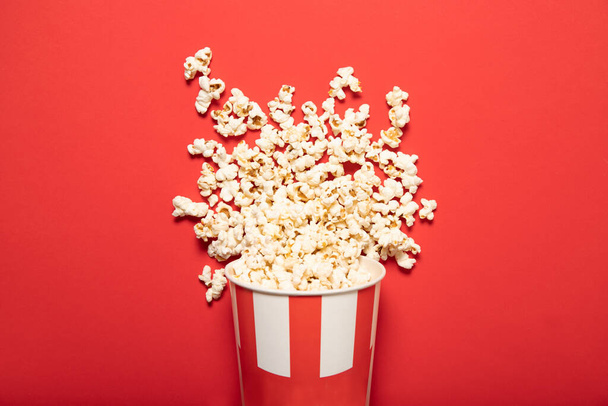 Papierbecher mit Popcorn auf rotem Hintergrund - Foto, Bild