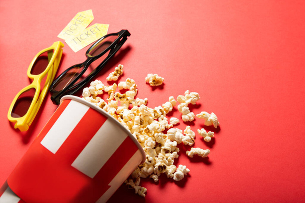 Pappbecher mit Popcorn auf rotem Hintergrund. Punkte und Kinokarten - Foto, Bild