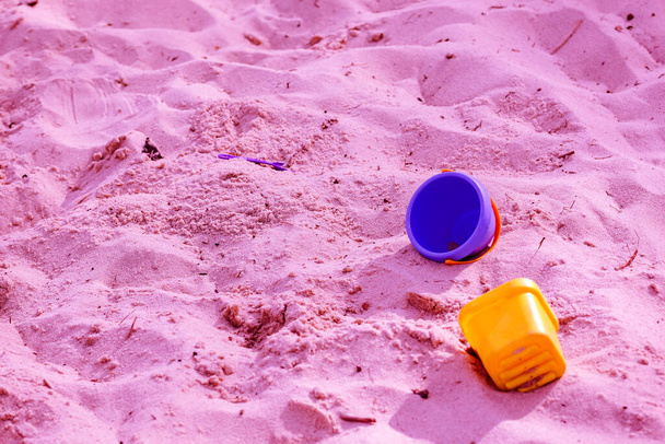 İki plastik çocuk oyuncağı kumsalda yatıyor. - Fotoğraf, Görsel