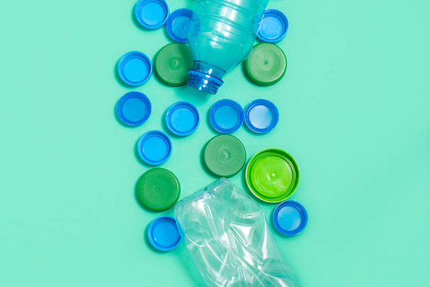 Composición de botellas de plástico y tapas de botellas de plástico sobre fondo verde con espacio para texto
 - Foto, Imagen