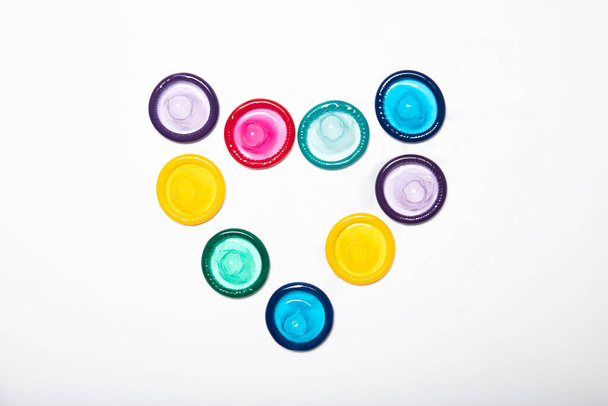 Värilliset kondomit sydämen muodossa valkoisella pohjalla
 - Valokuva, kuva