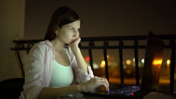 znudzona młoda kobieta pracuje z laptopem w nocy - Materiał filmowy, wideo