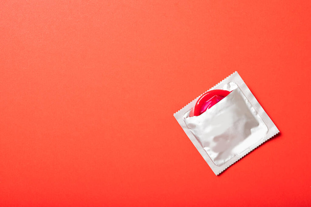 Kırmızı arka planda renkli prezervatif. Metin için yer, üst görünüm. İlaç ve sağlık hizmetleri - Fotoğraf, Görsel