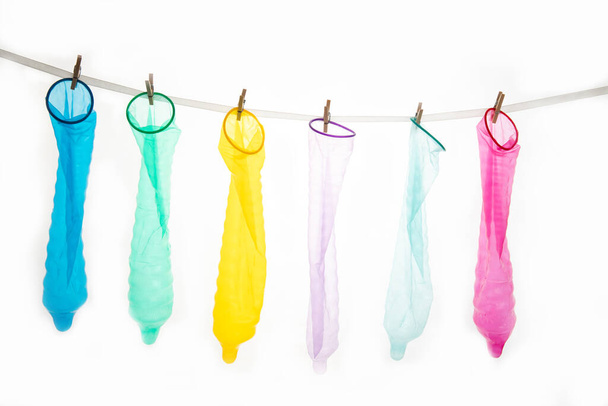 Barevné kondomy s špendlíky na provaze izolované na bílém. Antikoncepce - Fotografie, Obrázek