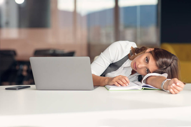 Jeune femme ennuyée habillée en chemise assise sur son lieu de travail
 - Photo, image