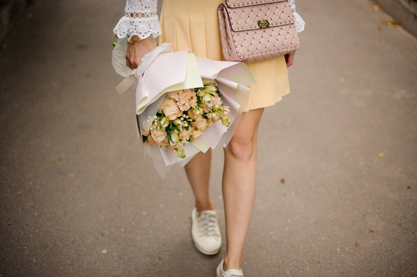 View of bouquet of roses in the hands of girl who walking in park - Φωτογραφία, εικόνα