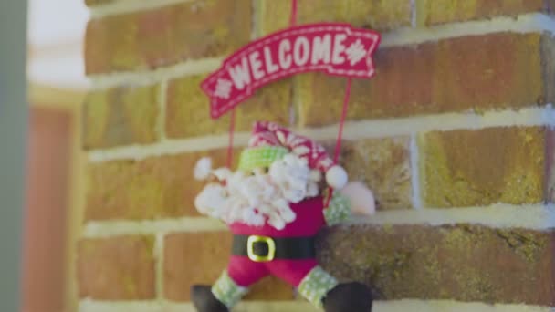 Spielzeug-Weihnachtsmann hängt an Wand mit WELCOME-Schild - Filmmaterial, Video