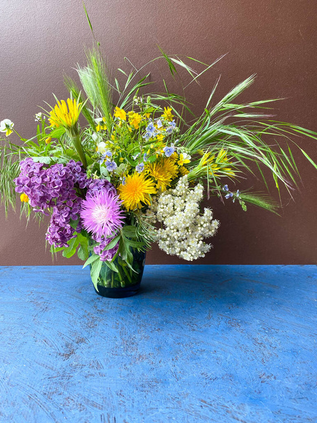Ένα μεγάλο μπουκέτο από φωτεινά πολύχρωμα άγρια λουλούδια σε ένα διακοσμητικό βάζο σε καφέ φόντο.Ελεύθερος χώρος.Defocus φως φόντο. - Φωτογραφία, εικόνα