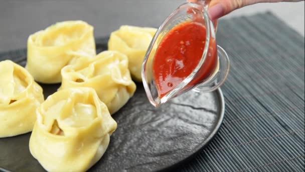 Nalanie sosu pomidorowego na talerz smacznymi orientalnymi pierogami - Materiał filmowy, wideo