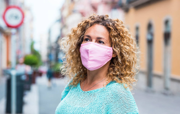 Portret pięknej dorosłej kobiety nosić maskę ochronną podczas coronavirus covid-19 zagrożenia zdrowia - Zdjęcie, obraz