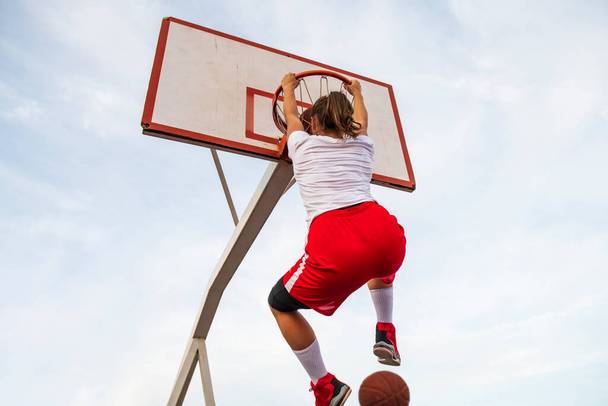 Females playing basketball on street court. Woman streetball player making slam dunk in a basketball game. - Foto, Imagen