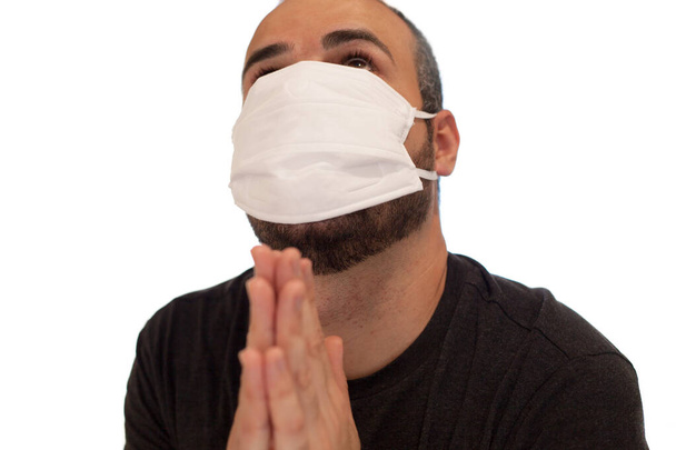 Mann mit Maske schützt sich vor dem Coronavirus, indem er mit den Händen betet - Foto, Bild