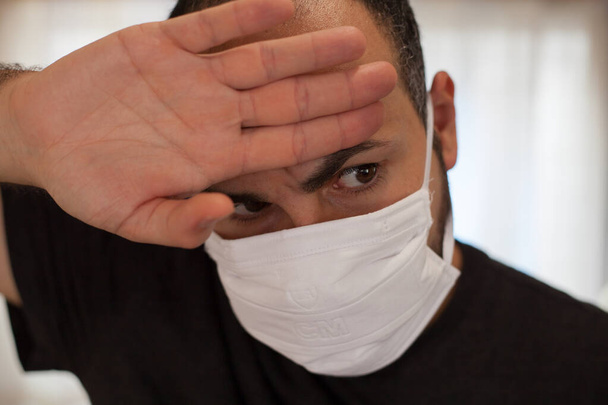Człowiek chory na koronawirusa nosi maskę i dotyka czoła z powodu dolegliwości, takich jak gorączka, zmęczenie i ból głowy.. - Zdjęcie, obraz