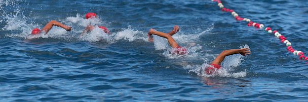 Gruppe von Schwimmern schwimmt im Meer bei den Wettkämpfen, Freiwassersport - Foto, Bild