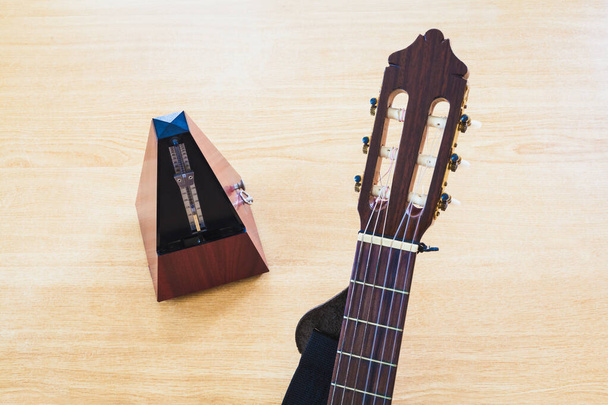 Guitar and musical metronome on wooden background - Photo, Image
