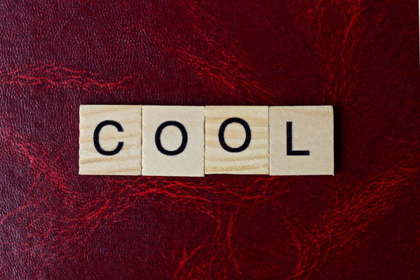 text the word cool from gray wooden small letters with black font on an red table - Photo, Image