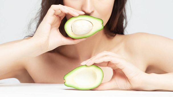 Young beautiful woman with avocado closeup. Skin care portrait. Freshness, fruit, nature - Photo, Image