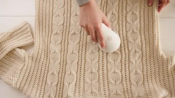 Vrouw verwijderen van pilling van gebreide trui met behulp van stof scheerapparaat - Video