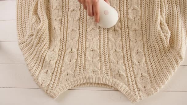 Žena odstraňuje piliny z pleteného svetru pomocí tkaniny holicí - Záběry, video