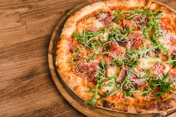 pizza with meat, bacon, arugula on a wooden background - Photo, Image