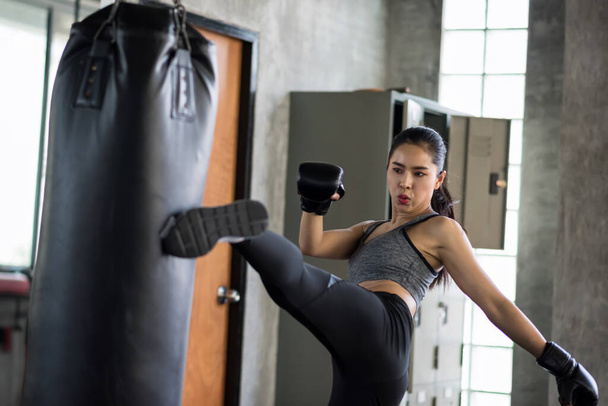 Strong muscle Asian boxing woman jump kick to huge punching bag at fitness gym. Athletic girl practice Muay Thai for bodybuilding and healthy lifestyle concept. workout in sport club. - Fotografie, Obrázek