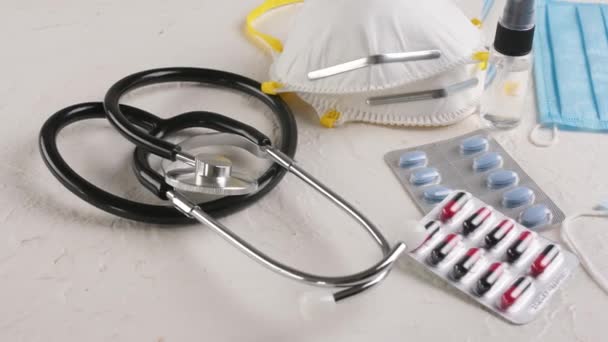 Stetoskop, koruyucu tıbbi maskeler, haplar ve beyaz arka planda dezenfektan. Coronavirüs salgını kavramı - Video, Çekim