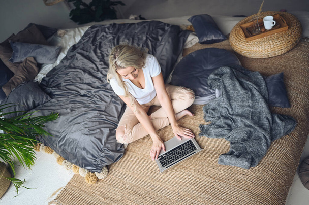 Happy beautiful blonde woman working, making video call, watching movie on a laptop in cozy home bedroom modern interior. Home quarantine Covid-19 pandemic Corona virus. Remote work from home concept. - Photo, Image