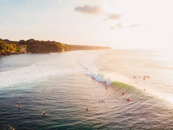 Aerial view of ocean with waves, surfers and warm light. Drone view in Bali - Photo, Image