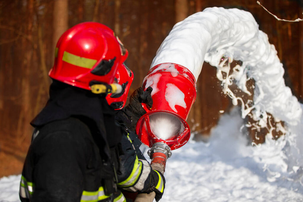 Firefighters extinguish a fire. Rescuers with fire hoses with foam. - Fotografie, Obrázek