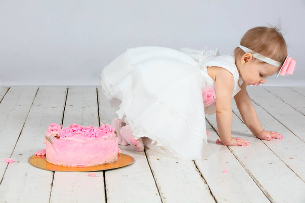 Eerste verjaardag. Klein meisje met een feestelijke roze taart. - Foto, afbeelding