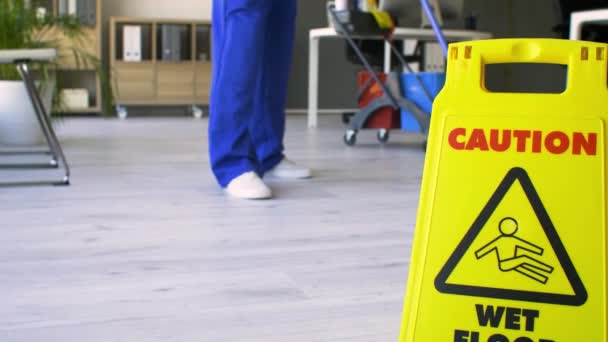 Janitor mopping floor in office, focus on caution sign - Footage, Video