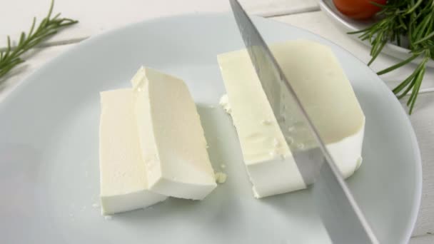 Ízletes feta sajt darabolása a tányéron - Felvétel, videó