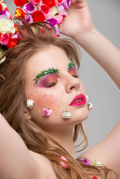 Retrato de uma menina bonita com maquiagem floral. Menina de verão em flores. O rosto de um modelo de luxo na imagem da primavera. O conceito de extensões de sobrancelha e pestanas. - Foto, Imagem