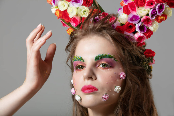 Beautiful girl in flower makeup. Spring or summer beauty. Fantastic woman with extended eyebrows and eyelashes. - 写真・画像