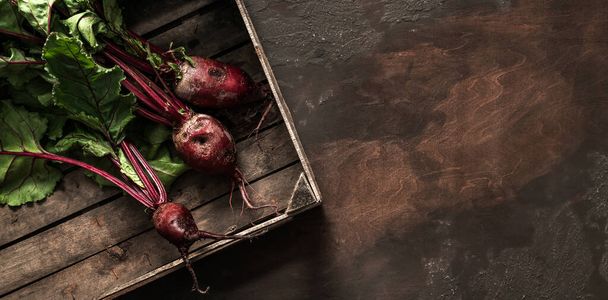 Beetroot in wooden box on dark background. Fresh vegetables, healthy organic food, harvest, agriculture, top view - Photo, Image