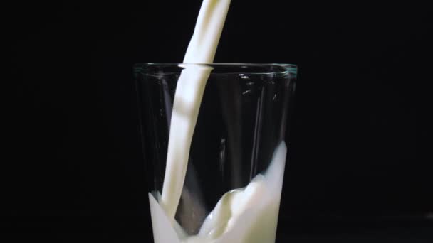 Pouring of fresh milk in glass on dark background - Footage, Video