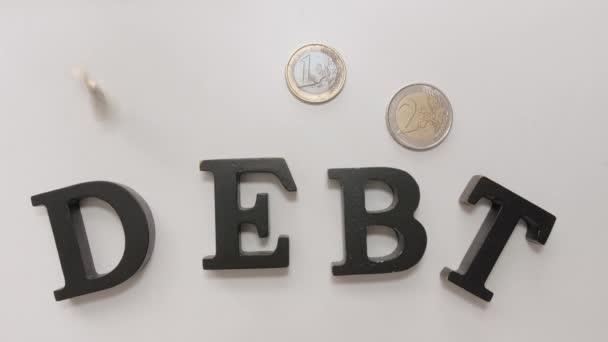 Mince se slovem DEBT na světlém pozadí, horní pohled - Záběry, video