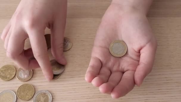 A nő érméket számol a fa asztalon. Az adósság fogalma - Felvétel, videó