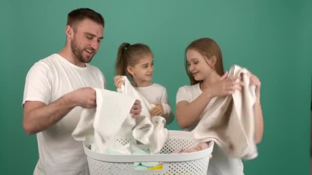 Ευτυχισμένη οικογένεια με καθαρά ρούχα στο καλάθι στο φόντο χρώμα - Πλάνα, βίντεο