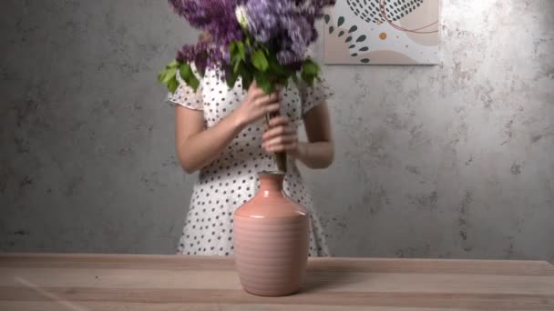 Vrouw zetten mooie lila bloemen in vaas thuis - Video