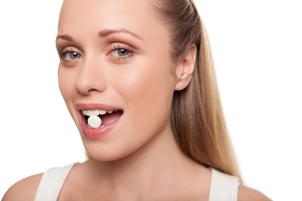 Portrait of young woman holding pill in her mouth - Photo, Image
