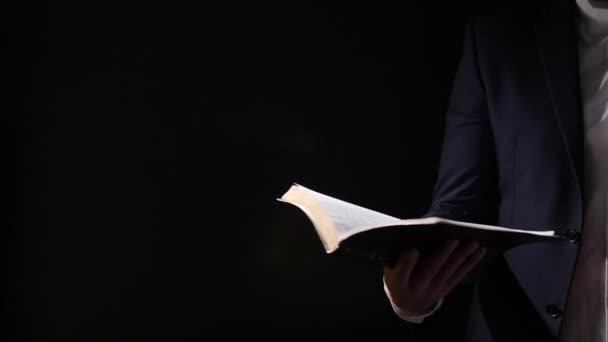 Mies, jolla on pyhä Raamattu pimeällä taustalla
 - Materiaali, video