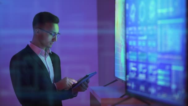 The man working with a tablet near the television on the hologram background - Footage, Video
