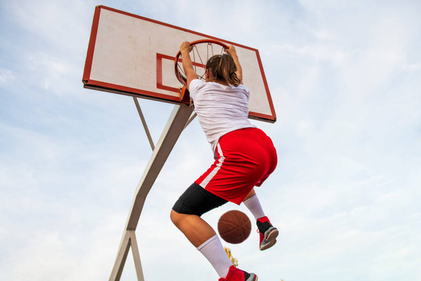 Females playing basketball on street court. Woman streetball player making slam dunk in a basketball game. - Photo, Image