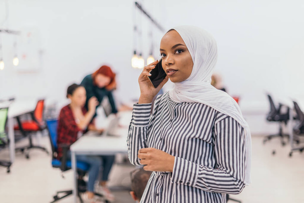 Young African American businesswoman talking on a smartphone in a modern startup office. Marketing concept. Multi-ethnic society. - Fotó, kép