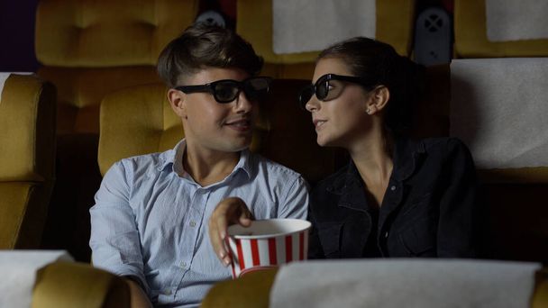 3Dメガネで映画を見ている映画館の男と女。画面を見て興味を持ちポップコーンを食べ - 写真・画像