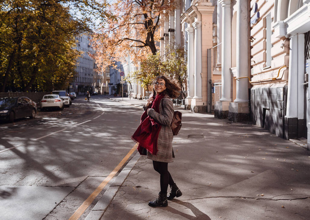 Portrait of beautiful brunette girl walking down the street. Smiling. Urban city scene. Warm sunny weather. Outdoors - Photo, Image