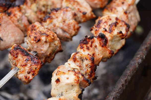 Close up of toasted shashlik on skewers. Succulent barbecue roasting on chargrill. - Foto, afbeelding